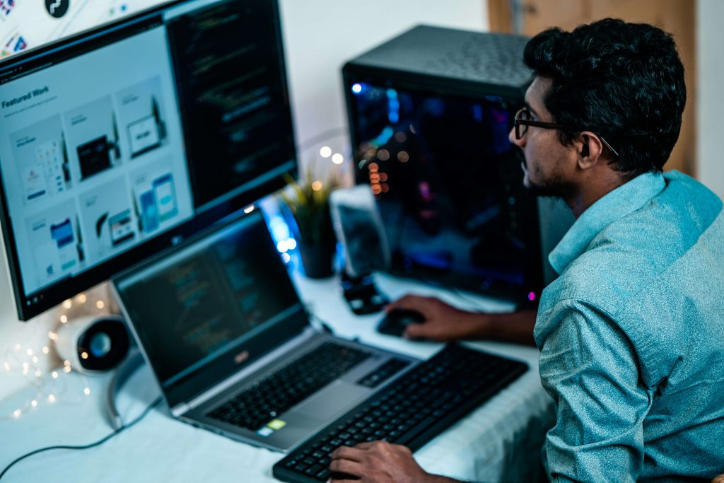 A man using a laptop and a desktop.